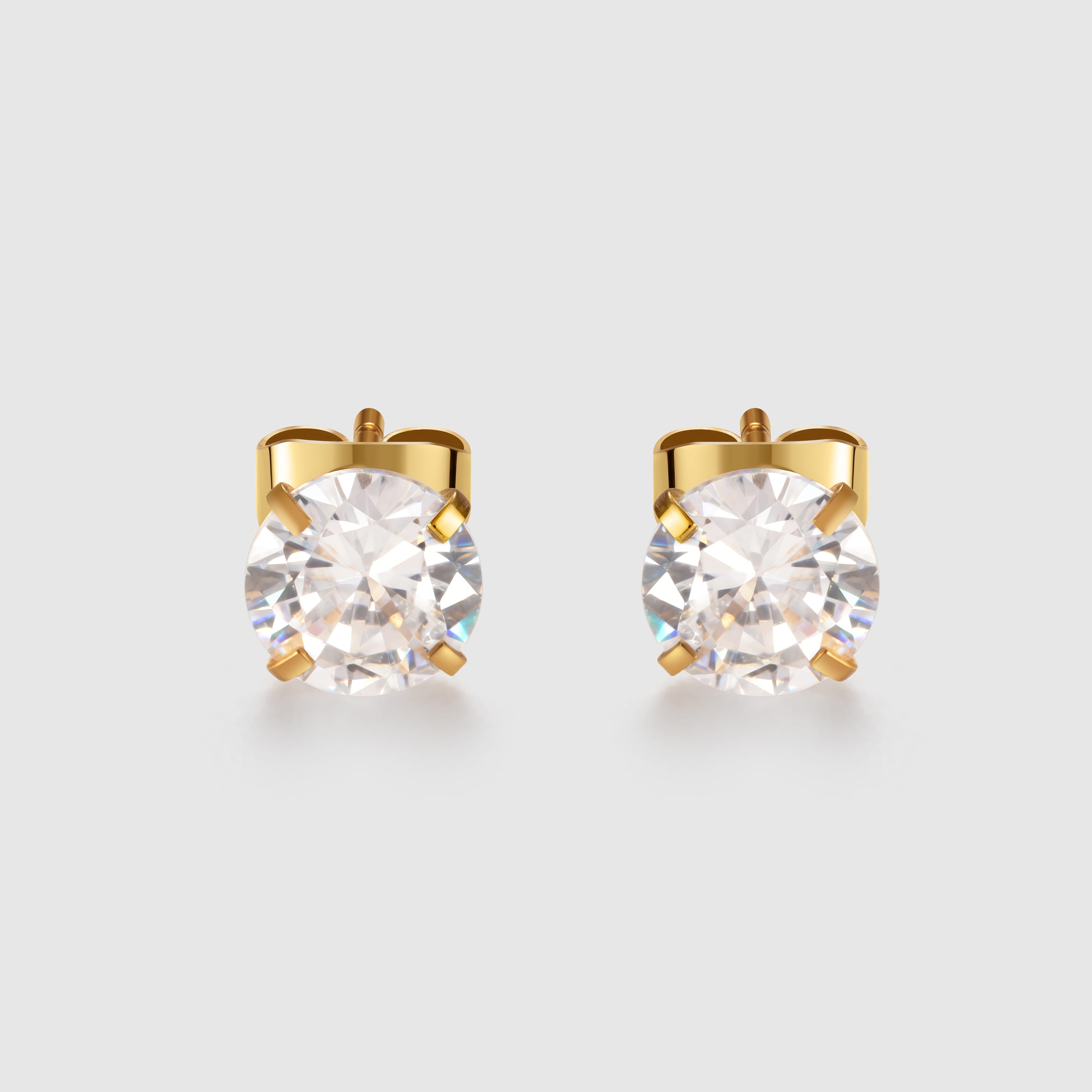 Gold stud earrings with clear gemstones on a light gray background