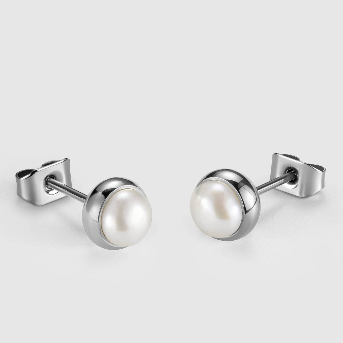 Pair of pearl stud earrings with silver posts on a light gray background