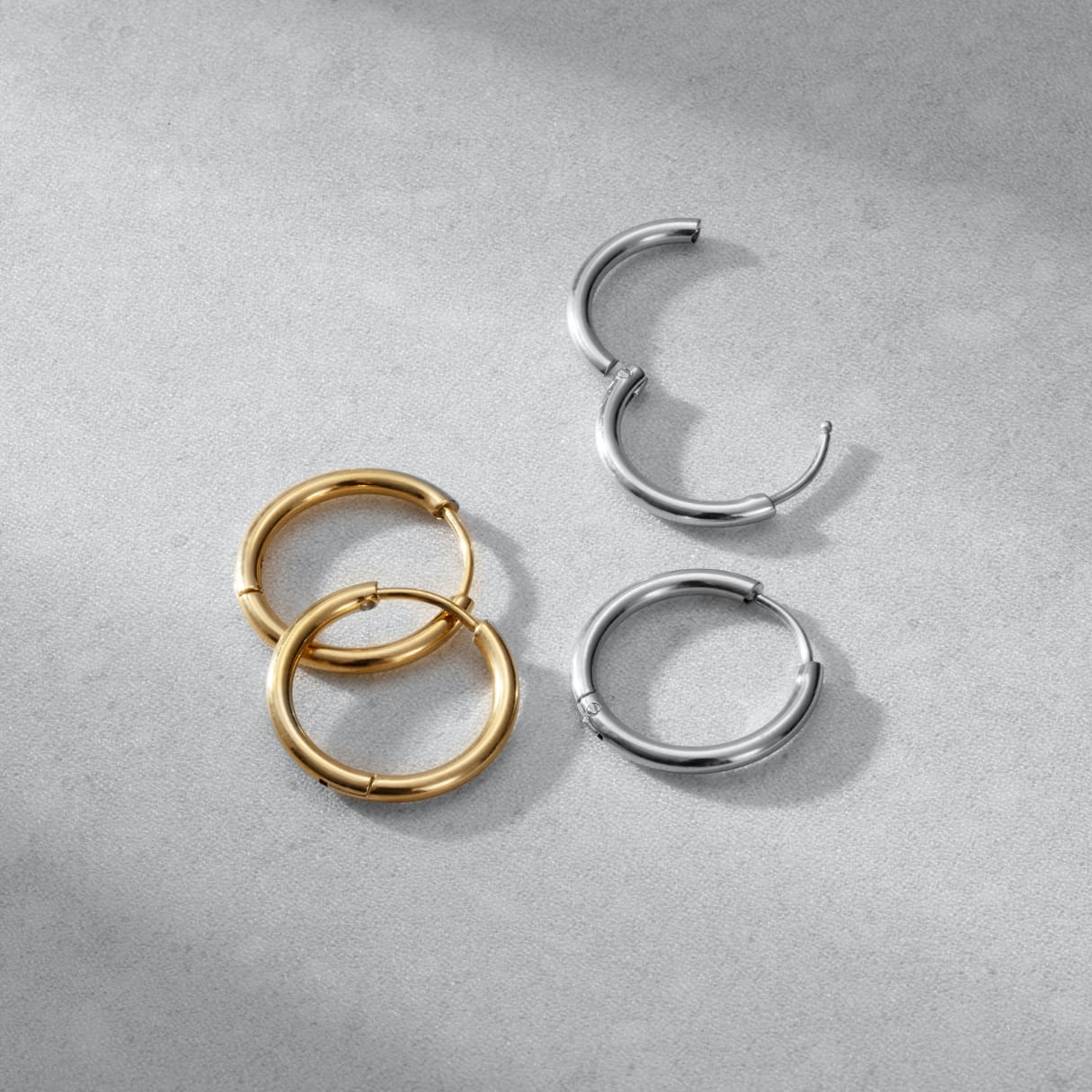 Three hoop earrings in gold, silver on a gray surface
