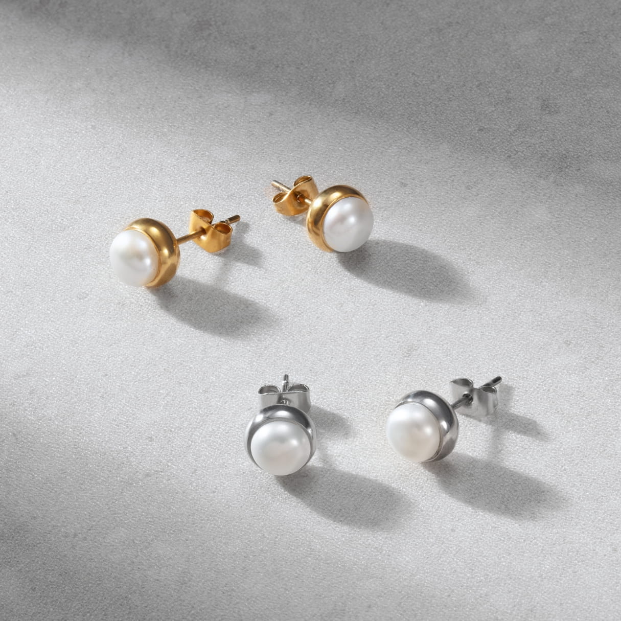 Set of pearl stud earrings in gold, silver on a gray surface