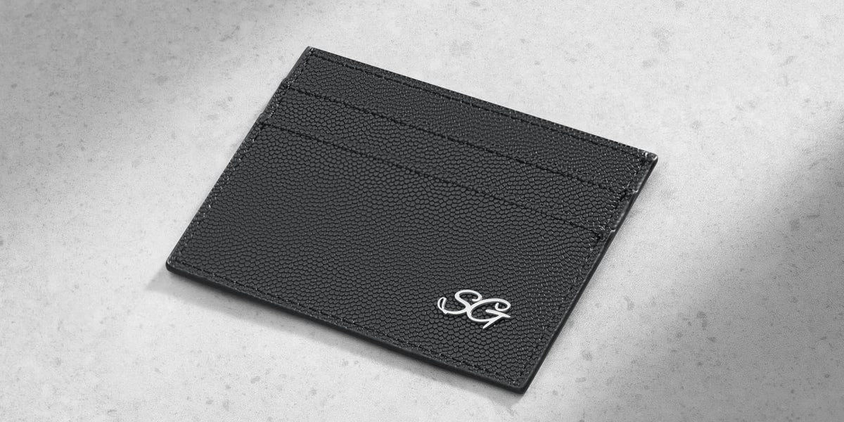 Black textured leather card holder with silver monogram initials.