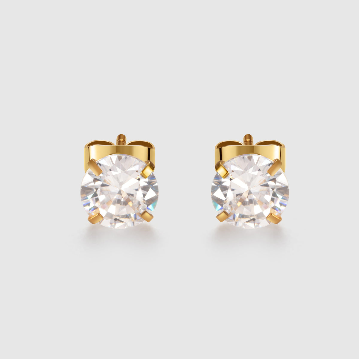 Gold stud earrings with clear gemstones on a light gray background