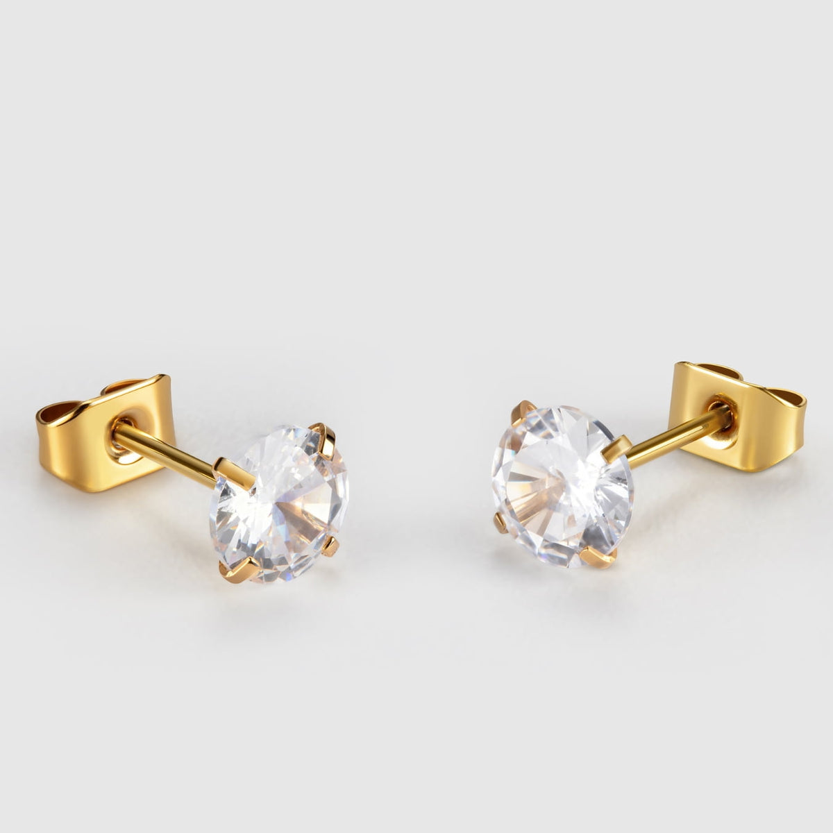 Gold earrings with clear gemstones on a light gray background