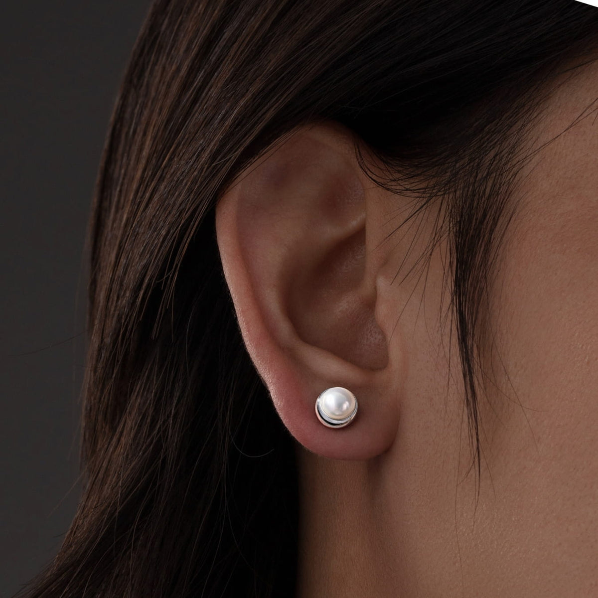 Close-up of an ear wearing a pearl earring with dark hair